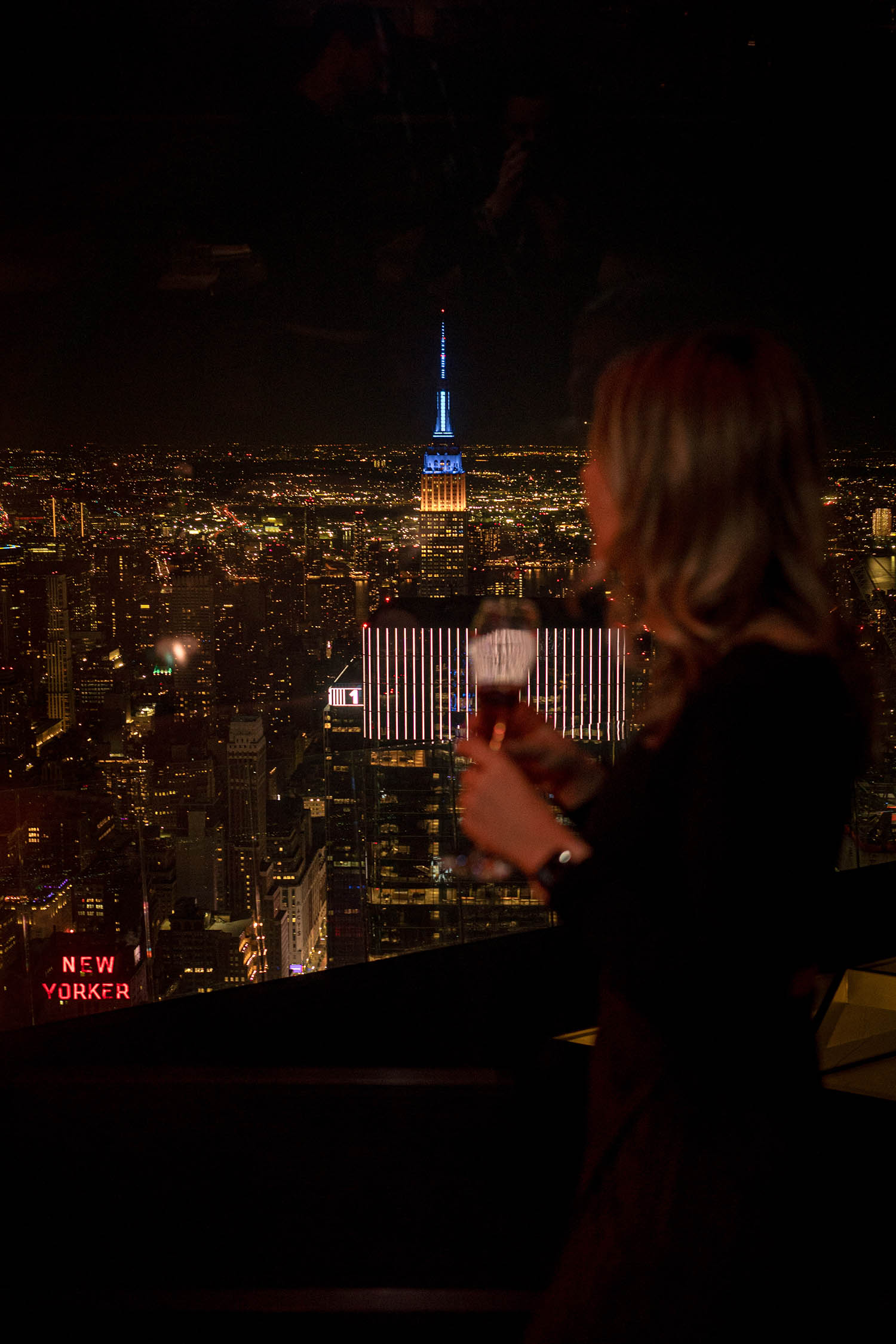 Woman silhouette at Peak Restaurant at night, Empire State building as the background
